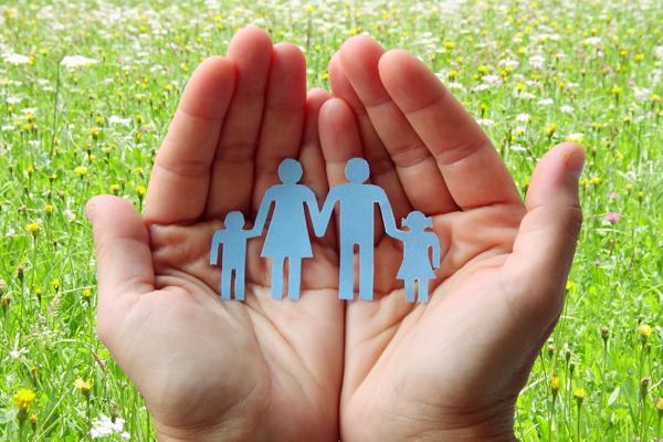 Hands holding a paper cutout of a family