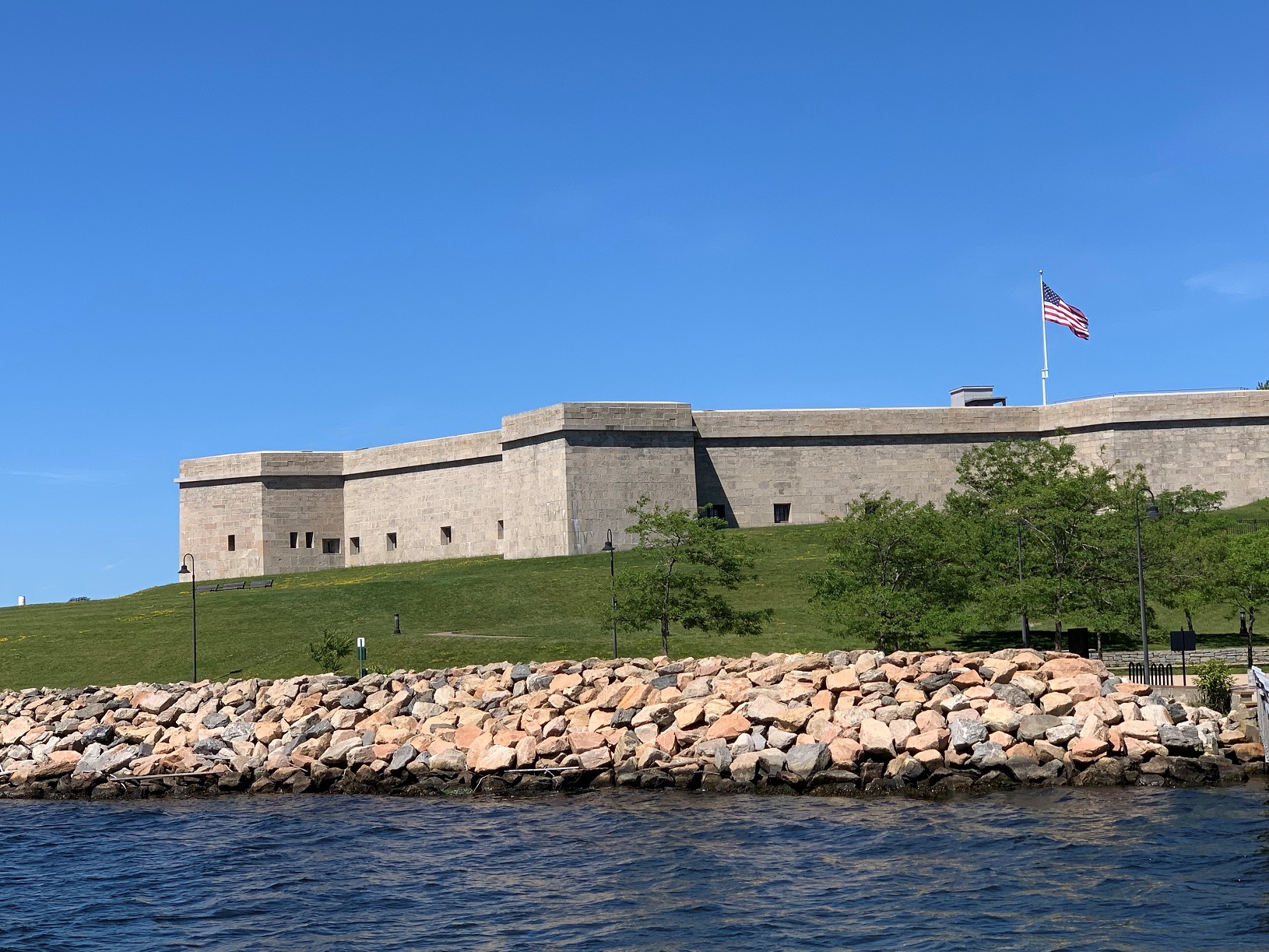 Fort Trumbull with American flag flying and river water in foreground