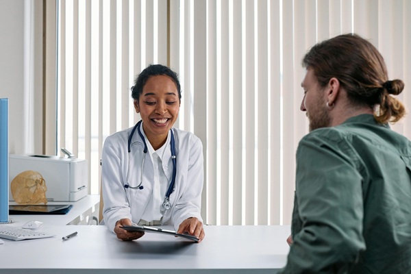Female doctor sitting down at a desk talking to a male patient