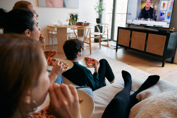 Family watching TV eating pizza