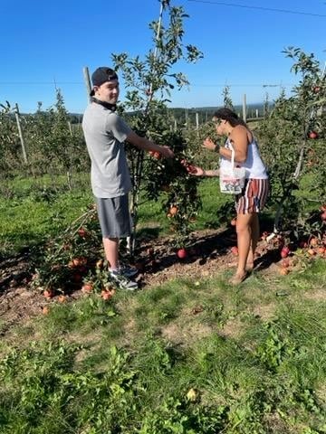 Zander and Kally pick apples.  Zander is turning his head towards the camera.