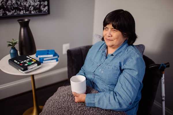 A Blind Woman Sitting by the Side of a Table Listening to a Talking Book