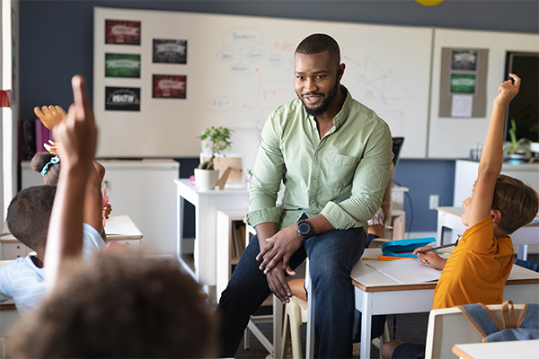 Teacher sitting on a desk.