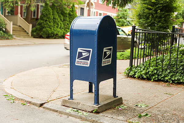 USPS blue mailbox on a neighborhood corner.