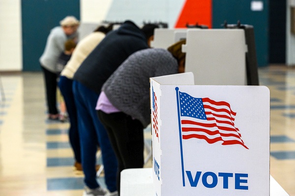 Several people in voting booths filling out ballots on Election Day