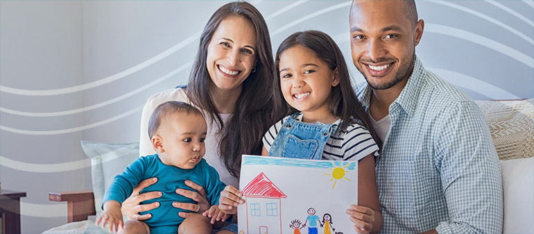 Photo of family holding up a young daughter's drawing in their home.