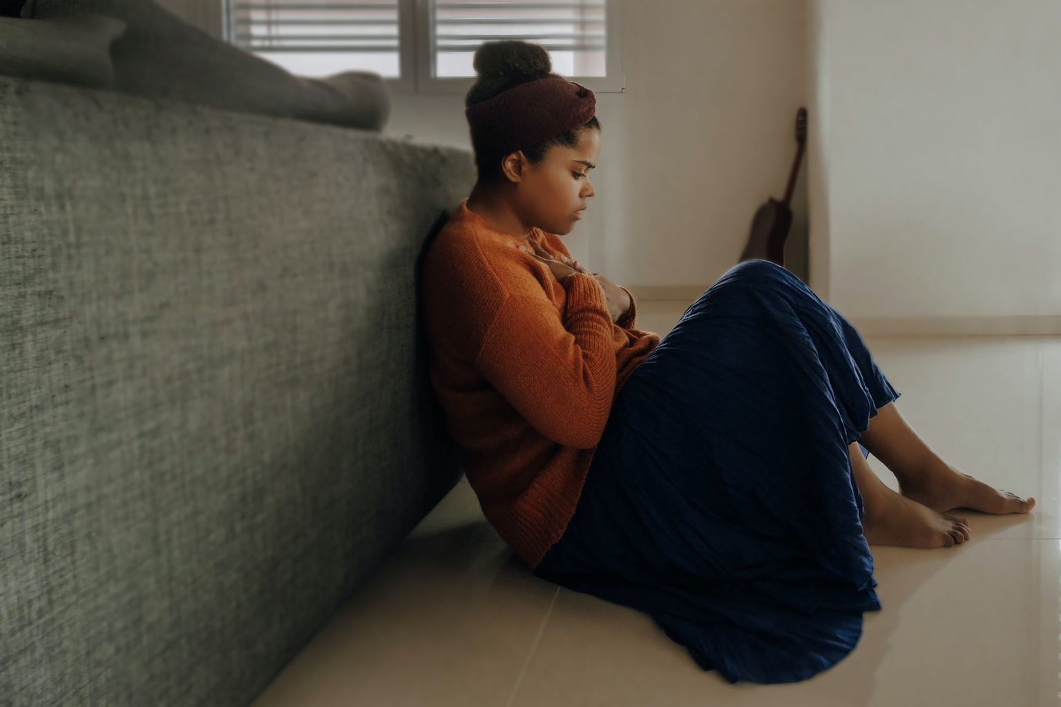 An individual sitting on the floor in their home