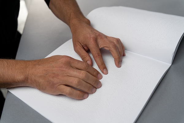 Braille Magazine with Two Hands and the Finger's Reading the Braille