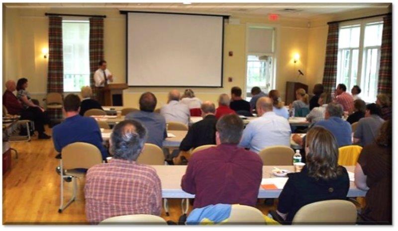 People attending a workshop, listening to a presenter. 
