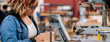 young woman works with wood in a workshop