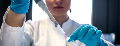 female scientist filling test tubes with liquid in a lab